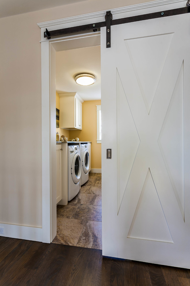 Foto di una sala lavanderia tradizionale di medie dimensioni con ante in stile shaker, ante bianche, top in granito, pareti gialle, pavimento con piastrelle in ceramica e lavatrice e asciugatrice affiancate