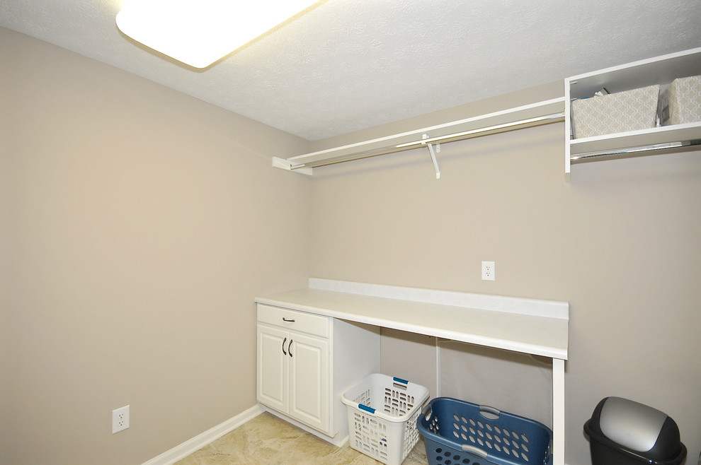 Ejemplo de cuarto de lavado lineal actual de tamaño medio con armarios con paneles con relieve, puertas de armario blancas, encimera de laminado, paredes grises y suelo de baldosas de cerámica
