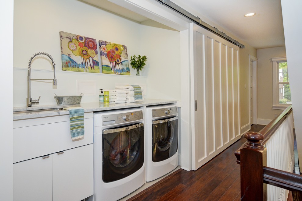 Inspiration for a medium sized traditional single-wall laundry cupboard in Newark with a submerged sink, flat-panel cabinets, white cabinets, marble worktops, beige walls, dark hardwood flooring and a side by side washer and dryer.