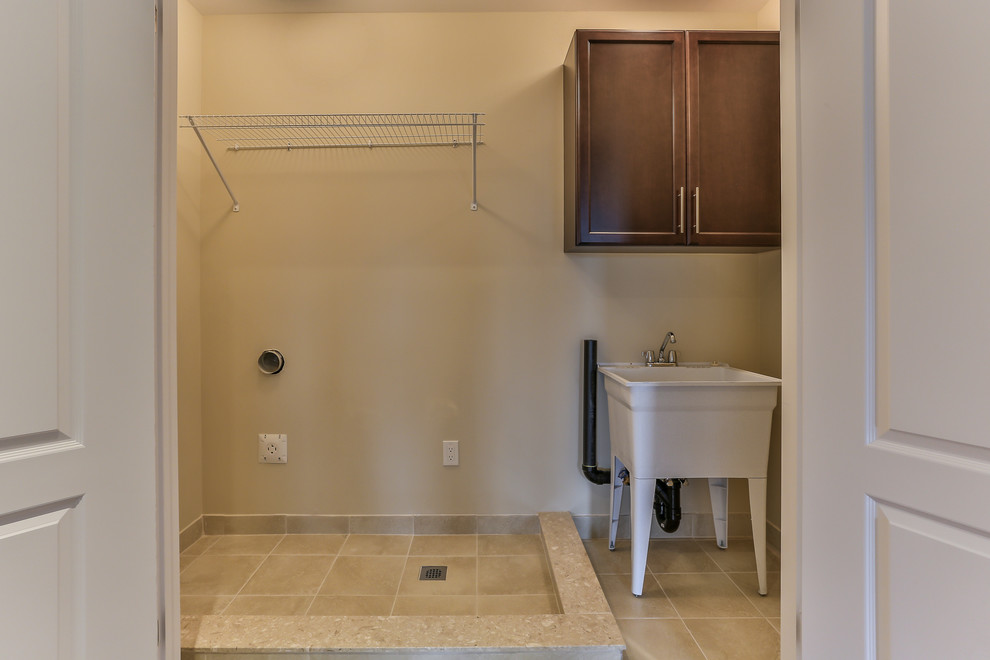 Idee per una sala lavanderia chic di medie dimensioni con lavatoio, pareti beige, pavimento con piastrelle in ceramica, pavimento beige, ante in stile shaker e ante in legno bruno