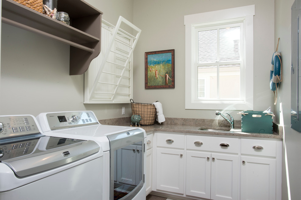 Landhaus Waschküche in L-Form mit Unterbauwaschbecken, Schrankfronten im Shaker-Stil, weißen Schränken, grauer Wandfarbe und Waschmaschine und Trockner nebeneinander in Charleston