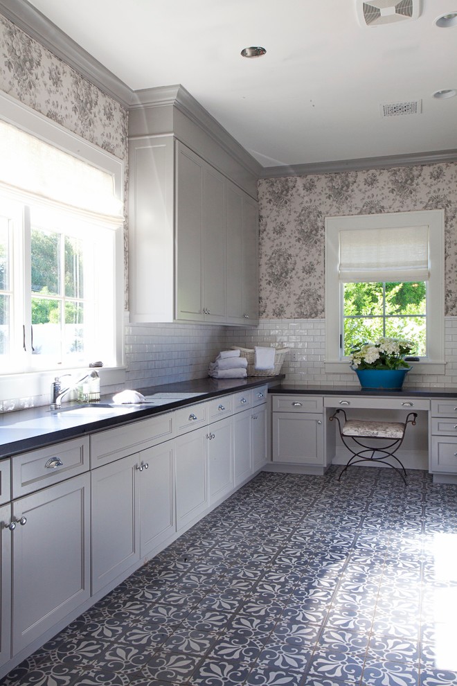 Inspiration för stora klassiska u-formade tvättstugor enbart för tvätt, med en undermonterad diskho, luckor med infälld panel, bänkskiva i täljsten, klinkergolv i keramik, en tvättmaskin och torktumlare bredvid varandra, flerfärgat golv, grå skåp och grå väggar