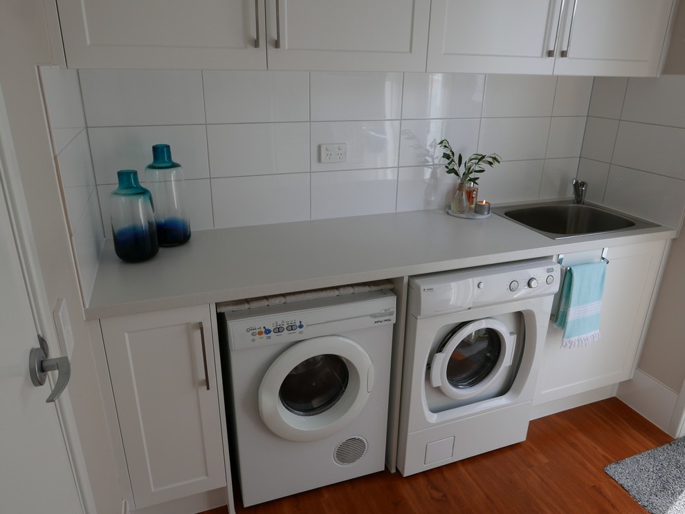 Bild på en liten maritim parallell tvättstuga enbart för tvätt, med en nedsänkt diskho, skåp i shakerstil, vita skåp, bänkskiva i kvarts och en tvättmaskin och torktumlare bredvid varandra
