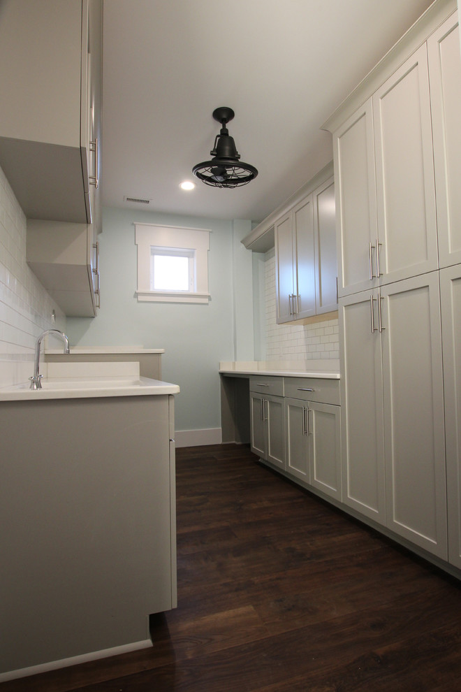 Großer Klassischer Hauswirtschaftsraum mit weißer Wandfarbe, dunklem Holzboden und braunem Boden in Wilmington