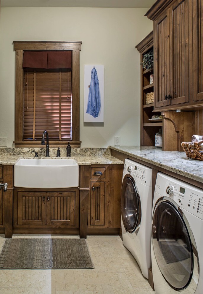 Example of a large classic l-shaped porcelain tile and beige floor dedicated laundry room design in Charlotte with a farmhouse sink, shaker cabinets, dark wood cabinets, granite countertops, beige walls and a side-by-side washer/dryer