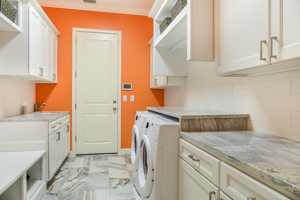 Exempel på ett stort klassiskt parallellt grovkök, med en undermonterad diskho, skåp i shakerstil, vita skåp, granitbänkskiva, orange väggar, klinkergolv i porslin och en tvättmaskin och torktumlare bredvid varandra