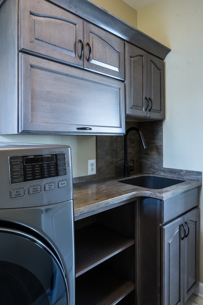 Inredning av en klassisk tvättstuga, med luckor med upphöjd panel, grå skåp, bänkskiva i koppar, en tvättmaskin och torktumlare bredvid varandra och en undermonterad diskho