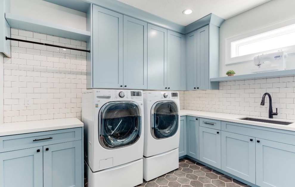 Idee per una sala lavanderia tradizionale di medie dimensioni con lavello sottopiano, ante con riquadro incassato, ante blu, top in quarzo composito, lavatrice e asciugatrice affiancate e top bianco