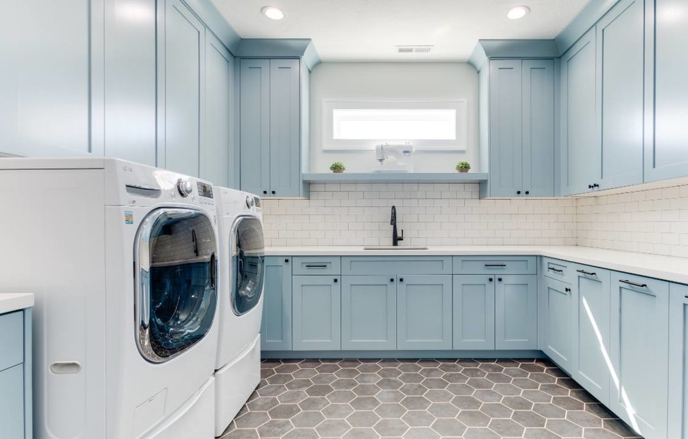Idee per una sala lavanderia chic di medie dimensioni con lavello sottopiano, ante con riquadro incassato, ante blu, top in quarzo composito, pareti bianche, pavimento con piastrelle in ceramica, lavatrice e asciugatrice affiancate, pavimento grigio e top bianco