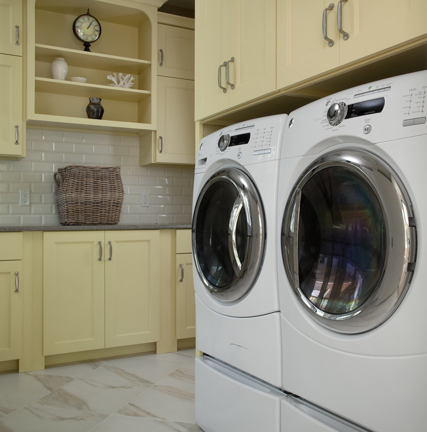 Esempio di una grande lavanderia multiuso classica con ante con riquadro incassato, ante gialle, pavimento in gres porcellanato e lavatrice e asciugatrice affiancate
