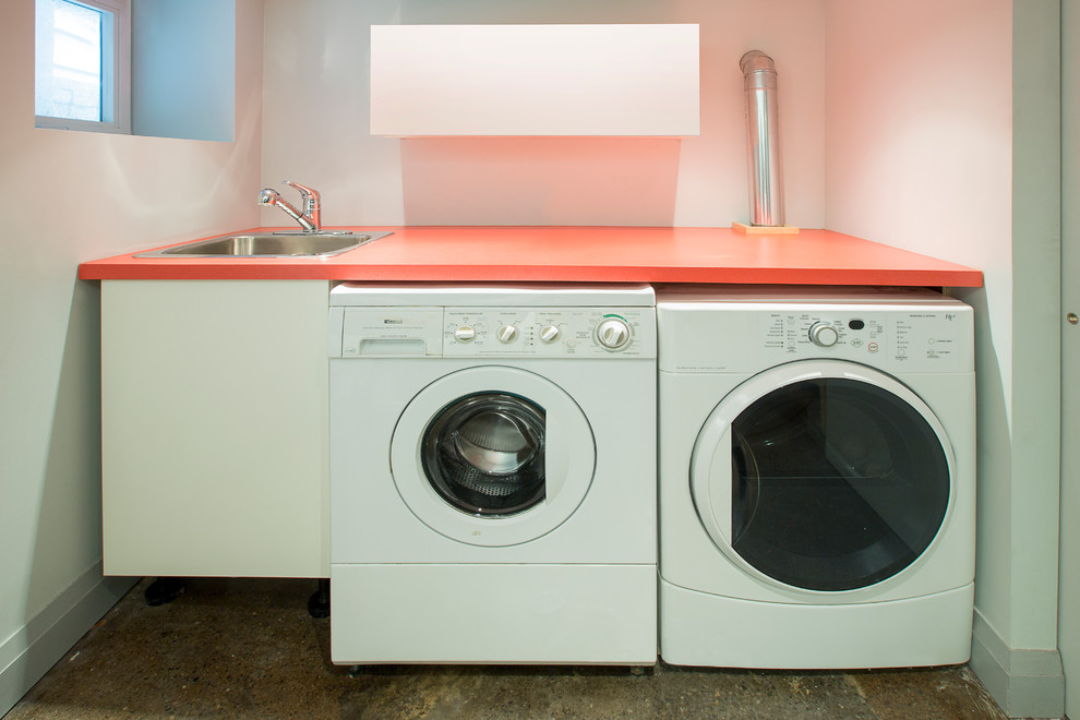 Idee per una sala lavanderia minimal di medie dimensioni con lavello da incasso, ante lisce, ante bianche, top in laminato, pavimento in cemento e lavatrice e asciugatrice affiancate