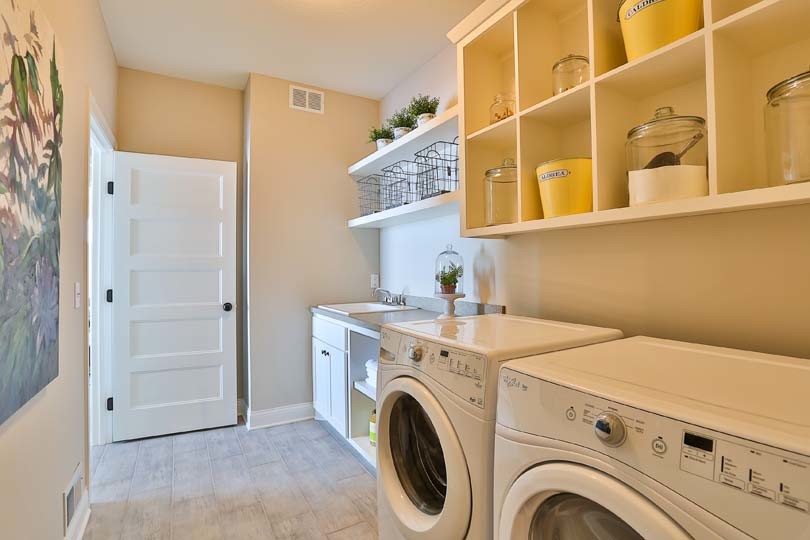 Example of a mid-sized classic single-wall vinyl floor utility room design in Minneapolis with a drop-in sink, open cabinets, white cabinets, laminate countertops, beige walls and a side-by-side washer/dryer