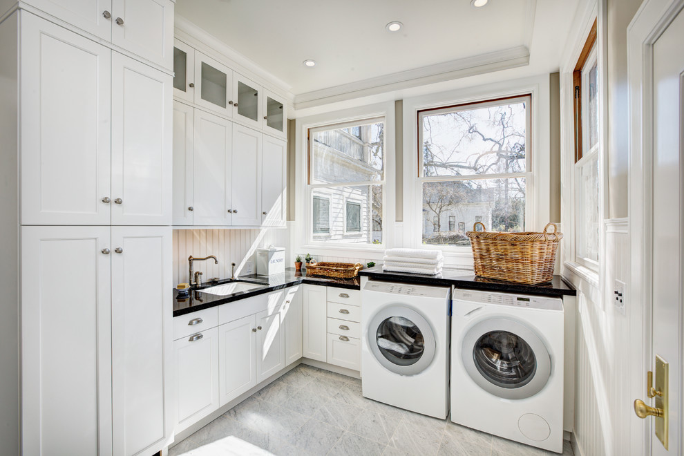 Inspiration för mycket stora klassiska l-formade tvättstugor enbart för tvätt, med vita skåp, en undermonterad diskho, skåp i shakerstil, bänkskiva i kvarts, vita väggar, marmorgolv, en tvättmaskin och torktumlare bredvid varandra och grått golv