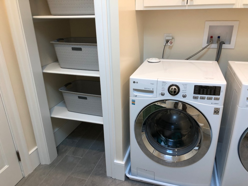 Inspiration for a mid-sized country single-wall ceramic tile and gray floor utility room remodel in Philadelphia with an utility sink, shaker cabinets, white cabinets, white walls and a side-by-side washer/dryer