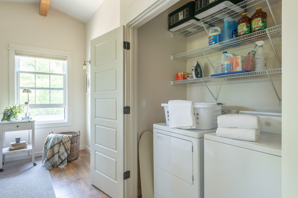 Foto di un piccolo ripostiglio-lavanderia chic con nessun'anta, ante bianche, pareti beige, pavimento in legno massello medio, lavatrice e asciugatrice affiancate e pavimento marrone