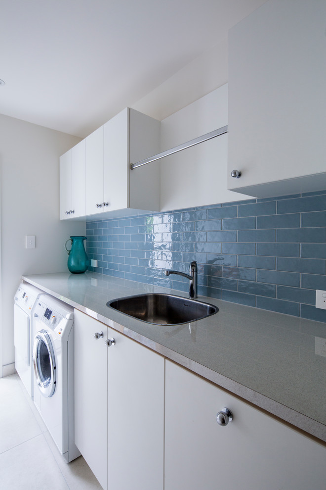 Design ideas for a medium sized contemporary single-wall separated utility room in Christchurch with a single-bowl sink, white cabinets, laminate countertops, porcelain flooring and a side by side washer and dryer.