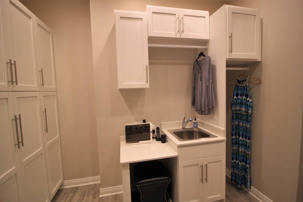 インディアナポリスにあるトランジショナルスタイルのおしゃれな家事室 (ドロップインシンク、シェーカースタイル扉のキャビネット、白いキャビネット、クッションフロア、左右配置の洗濯機・乾燥機、グレーの床) の写真