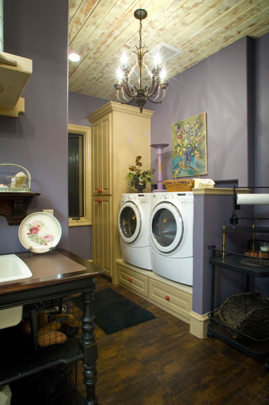 Foto di una lavanderia country di medie dimensioni con ante con bugna sagomata, pareti viola, lavatrice e asciugatrice affiancate, ante bianche e parquet scuro