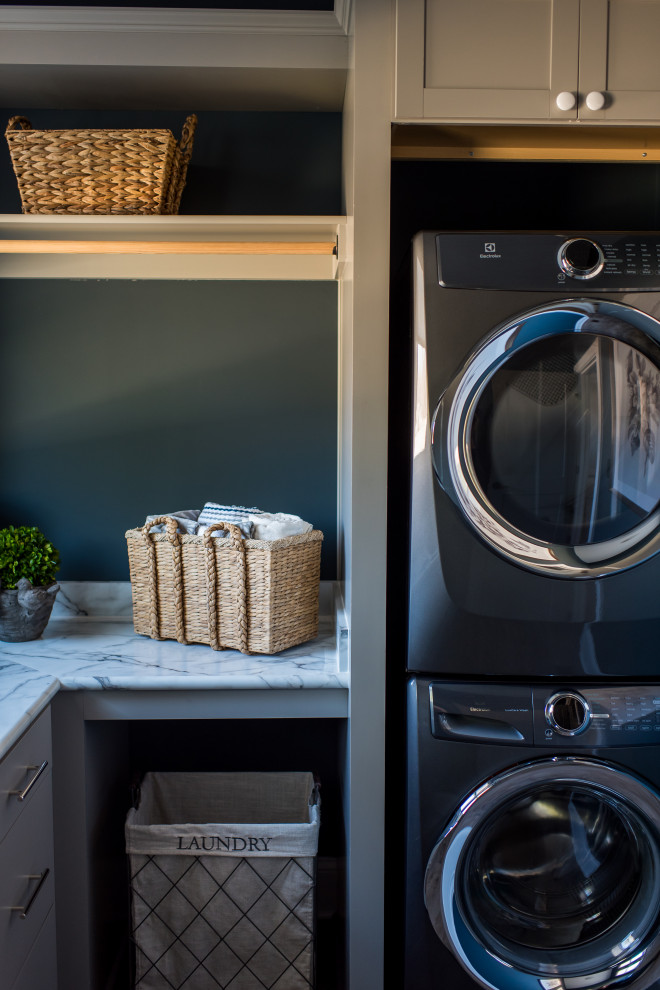 Idéer för att renovera en mellanstor funkis grå l-formad grått tvättstuga enbart för tvätt, med en nedsänkt diskho, skåp i shakerstil, grå skåp, blå väggar, mellanmörkt trägolv, en tvättpelare och brunt golv