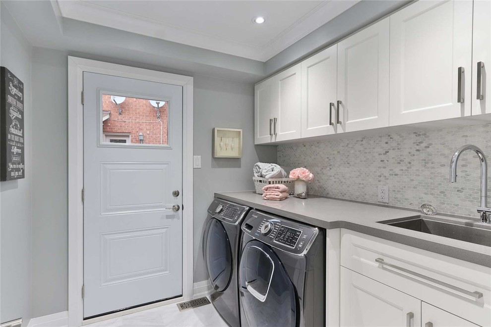 Small minimalist galley vinyl floor and gray floor dedicated laundry room photo in Philadelphia with an undermount sink, shaker cabinets, white cabinets, laminate countertops, gray walls, a side-by-side washer/dryer and gray countertops
