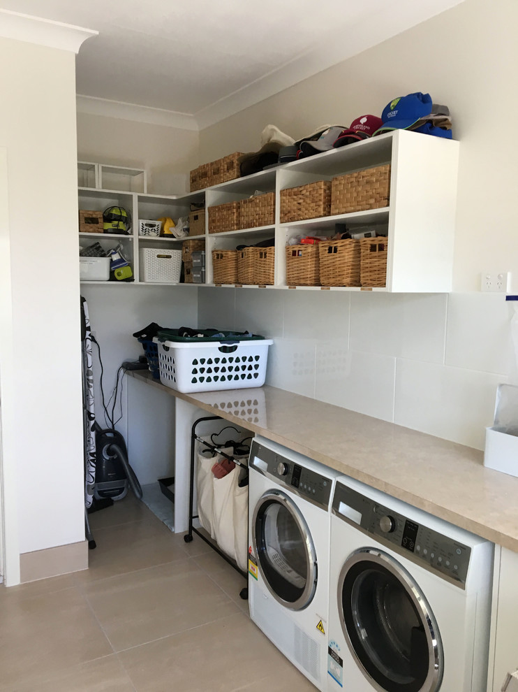 Einzeilige, Kleine Moderne Waschküche mit offenen Schränken, weißen Schränken, Granit-Arbeitsplatte, weißer Wandfarbe, Keramikboden, Waschmaschine und Trockner nebeneinander und beigem Boden in Brisbane