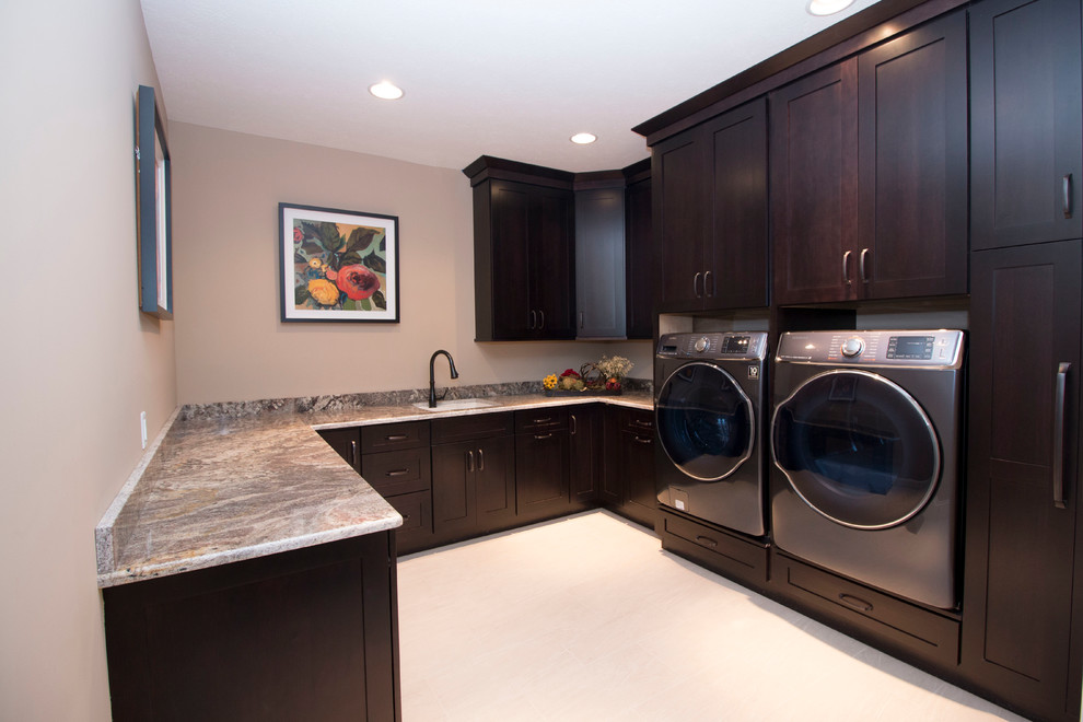 Large modern u-shaped laundry cupboard in Other with a submerged sink, shaker cabinets, dark wood cabinets, granite worktops, beige walls, ceramic flooring and a side by side washer and dryer.