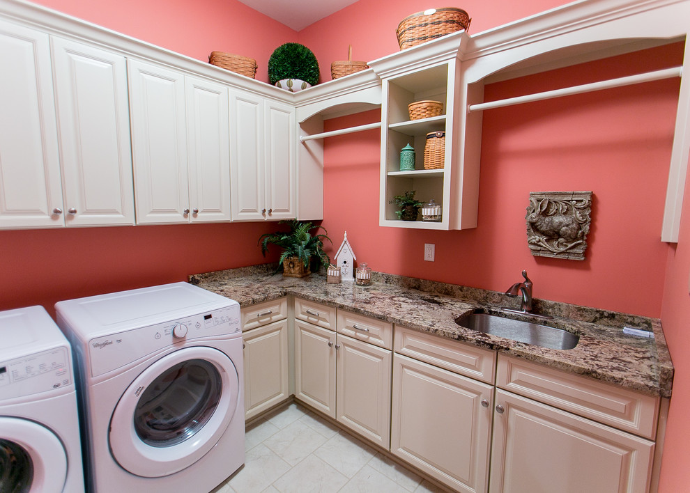 ルイビルにあるラグジュアリーな広いトランジショナルスタイルのおしゃれな洗濯室 (L型、アンダーカウンターシンク、レイズドパネル扉のキャビネット、白いキャビネット、御影石カウンター、ピンクの壁、左右配置の洗濯機・乾燥機) の写真
