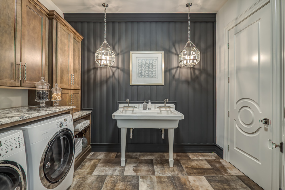 Inspiration for a large traditional single-wall separated utility room in Cincinnati with recessed-panel cabinets, medium wood cabinets, grey walls, a side by side washer and dryer, brown floors, an utility sink, granite worktops, porcelain flooring, multicoloured worktops and feature lighting.