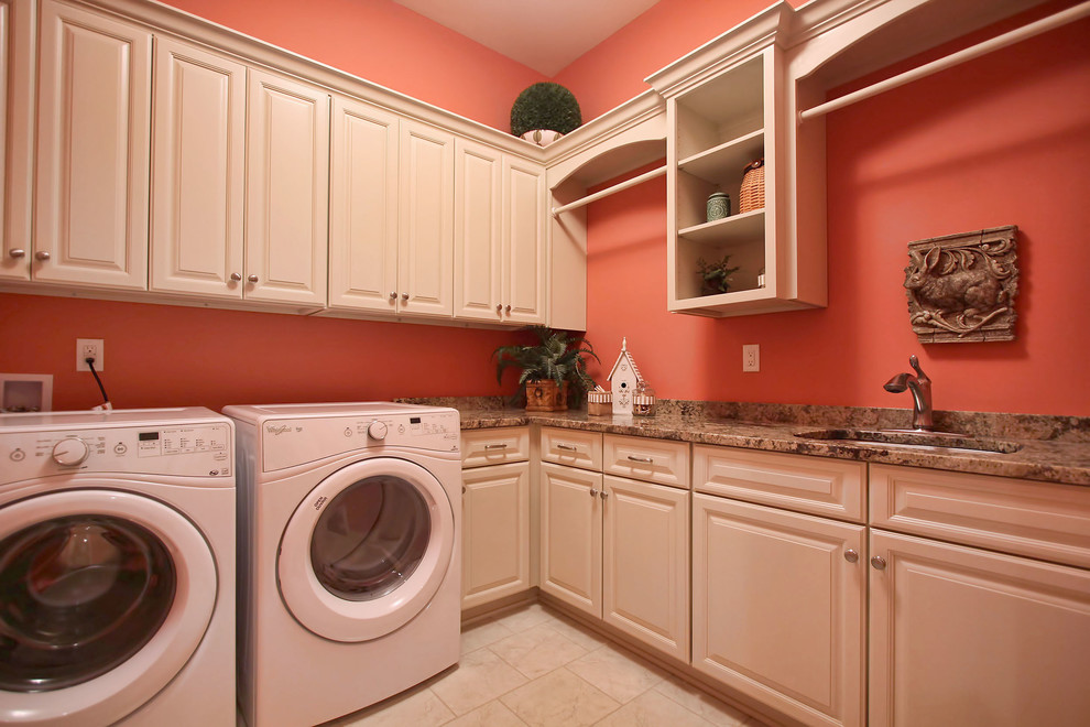 ルイビルにある高級な広いトラディショナルスタイルのおしゃれな洗濯室 (L型、アンダーカウンターシンク、レイズドパネル扉のキャビネット、白いキャビネット、御影石カウンター、ピンクの壁、セラミックタイルの床、左右配置の洗濯機・乾燥機) の写真