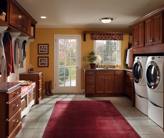 Esempio di una grande lavanderia multiuso chic con lavatoio, ante con bugna sagomata, ante in legno scuro, pareti gialle, pavimento con piastrelle in ceramica, lavatrice e asciugatrice affiancate e pavimento grigio