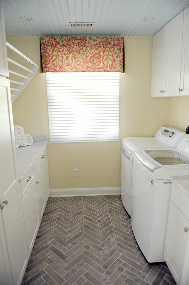 Inspiration for a small transitional galley ceramic tile and gray floor utility room remodel in Baltimore with an undermount sink, shaker cabinets, white cabinets, marble countertops, yellow walls and a side-by-side washer/dryer