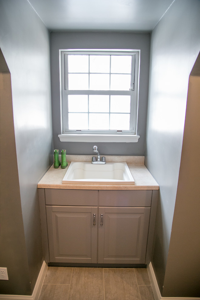 Foto di una sala lavanderia tradizionale di medie dimensioni con lavello da incasso, ante con bugna sagomata, ante bianche, pareti grigie, pavimento in gres porcellanato e lavatrice e asciugatrice affiancate