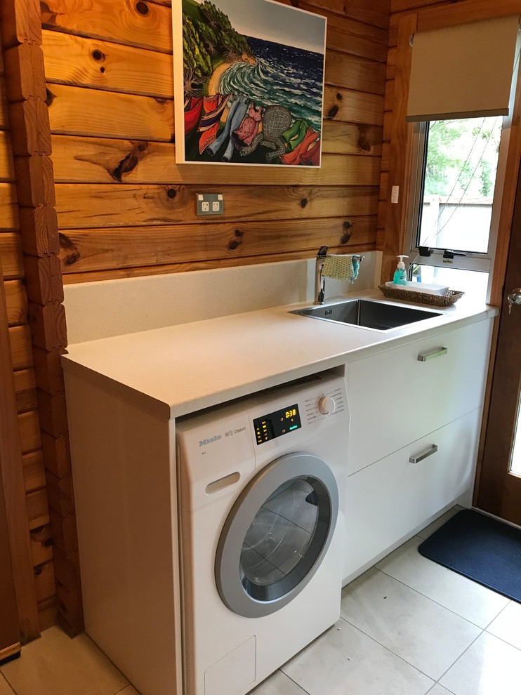 Zweizeilige, Kleine Moderne Waschküche mit Waschbecken, flächenbündigen Schrankfronten, weißen Schränken, Laminat-Arbeitsplatte, Porzellan-Bodenfliesen, grauem Boden und weißer Arbeitsplatte in Christchurch