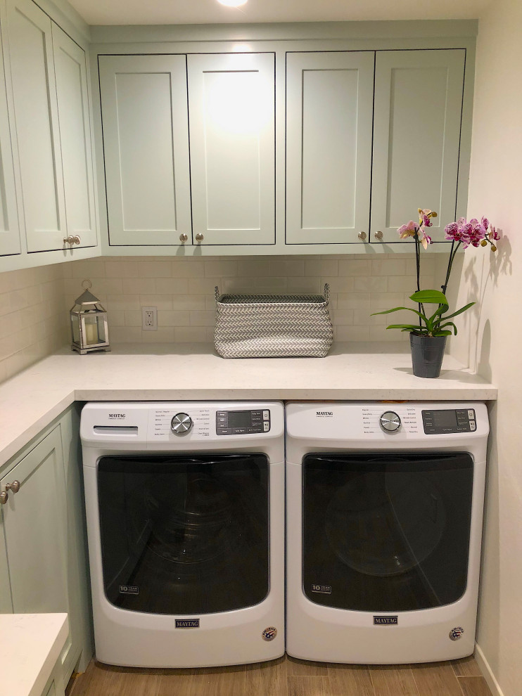 Inspiration for a small traditional utility room in Santa Barbara with an utility sink, shaker cabinets, green cabinets, engineered stone countertops, white walls, porcelain flooring, a side by side washer and dryer, brown floors and white worktops.