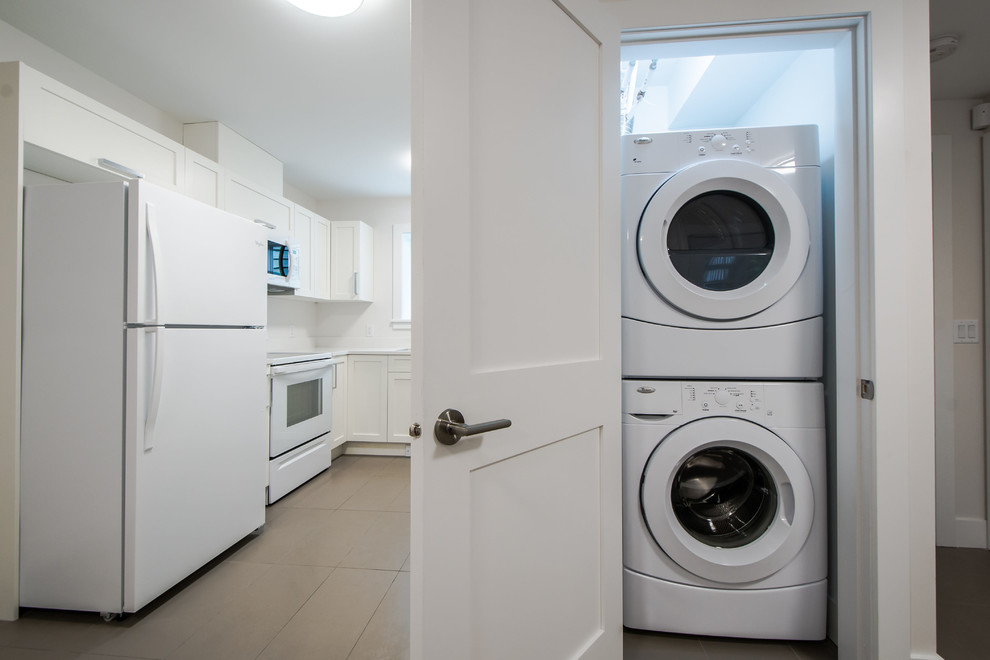 Kleiner Moderner Hauswirtschaftsraum mit Waschmaschinenschrank, Keramikboden und Waschmaschine und Trockner gestapelt in Vancouver