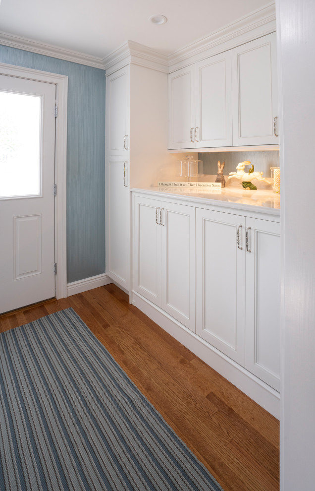 Foto di una lavanderia multiuso classica di medie dimensioni con ante bianche, pareti blu, pavimento in legno massello medio, lavatrice e asciugatrice affiancate e pavimento marrone