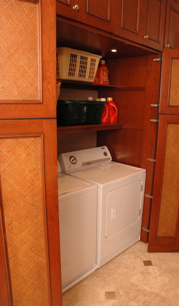 Immagine di un ripostiglio-lavanderia chic di medie dimensioni con ante con riquadro incassato, ante in legno scuro, pavimento in travertino e lavatrice e asciugatrice affiancate