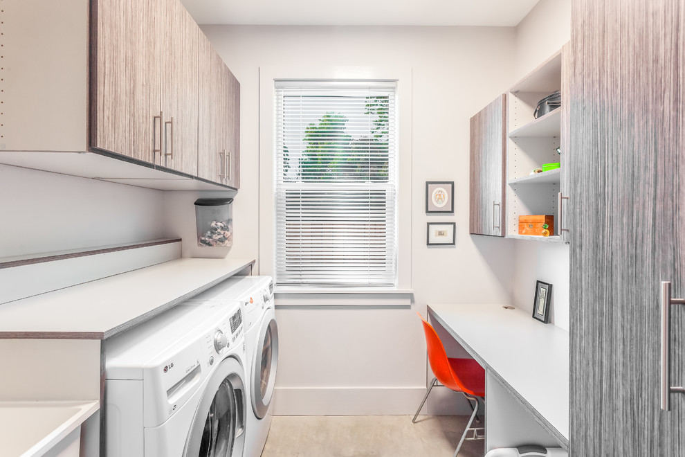 This is an example of a medium sized contemporary galley utility room in New Orleans with flat-panel cabinets, laminate countertops, white walls, concrete flooring, a side by side washer and dryer, grey floors, white worktops and grey cabinets.