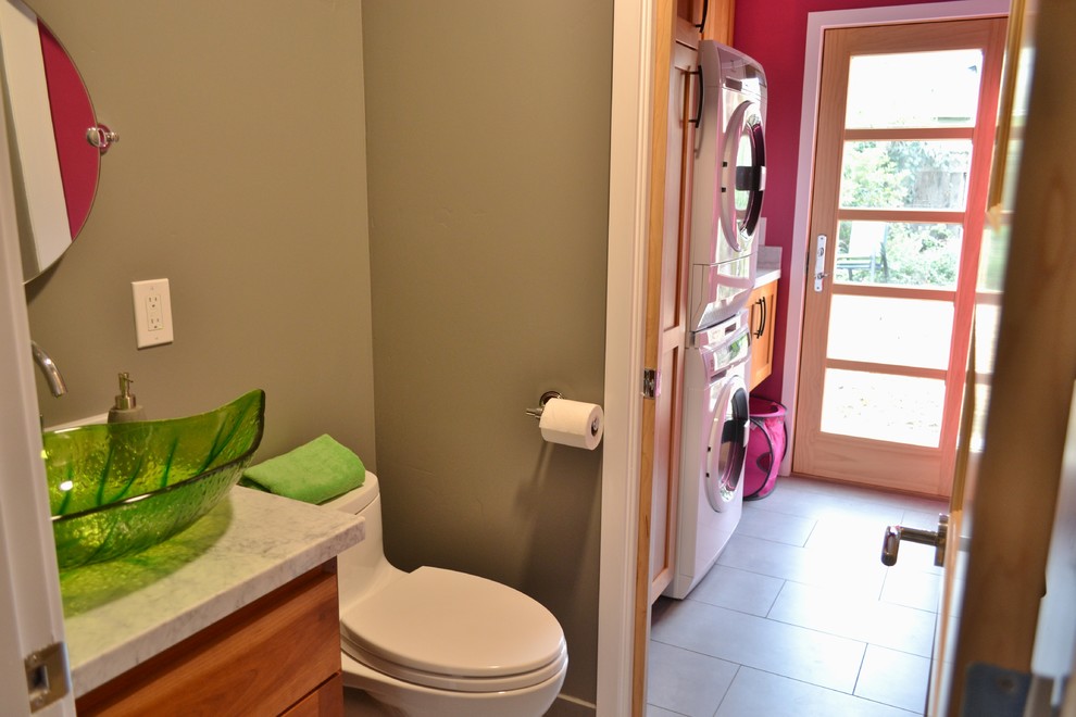 Immagine di una piccola lavanderia multiuso minimal con lavello sottopiano, ante in stile shaker, ante in legno bruno, top in granito, pareti rosa, pavimento in gres porcellanato e lavatrice e asciugatrice a colonna