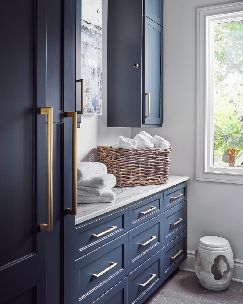 Dedicated laundry room - mid-sized transitional galley limestone floor and gray floor dedicated laundry room idea in Other with recessed-panel cabinets, blue cabinets, quartzite countertops, stone slab backsplash, white walls, a side-by-side washer/dryer and white countertops