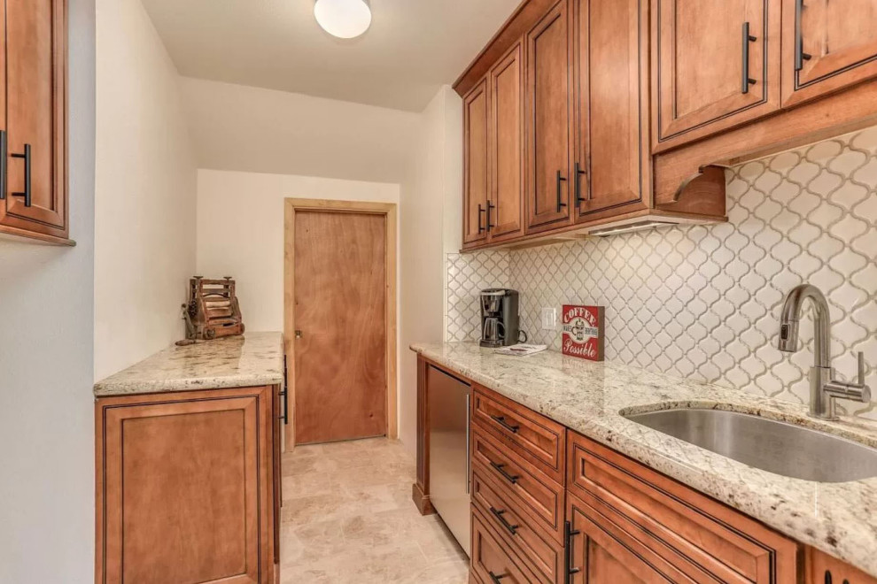 This is an example of a medium sized traditional galley utility room in San Diego with a submerged sink, raised-panel cabinets, brown cabinets, granite worktops, white splashback, cement tile splashback, white walls, carpet, a stacked washer and dryer, beige floors and beige worktops.