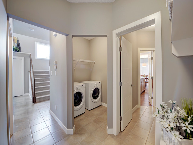 Foto di una sala lavanderia tradizionale di medie dimensioni con pareti grigie, pavimento con piastrelle in ceramica e lavatrice e asciugatrice affiancate