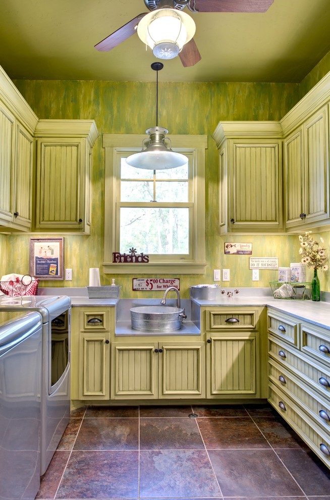 Foto på en rustik grå tvättstuga, med gröna väggar och en allbänk