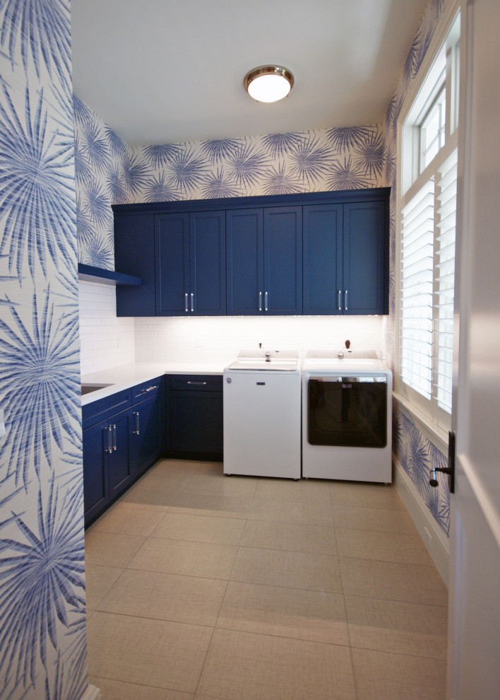 Foto på ett stort tropiskt vit l-format grovkök, med en undermonterad diskho, luckor med infälld panel, blå skåp, bänkskiva i kvartsit, flerfärgade väggar, klinkergolv i keramik, en tvättmaskin och torktumlare bredvid varandra och grått golv