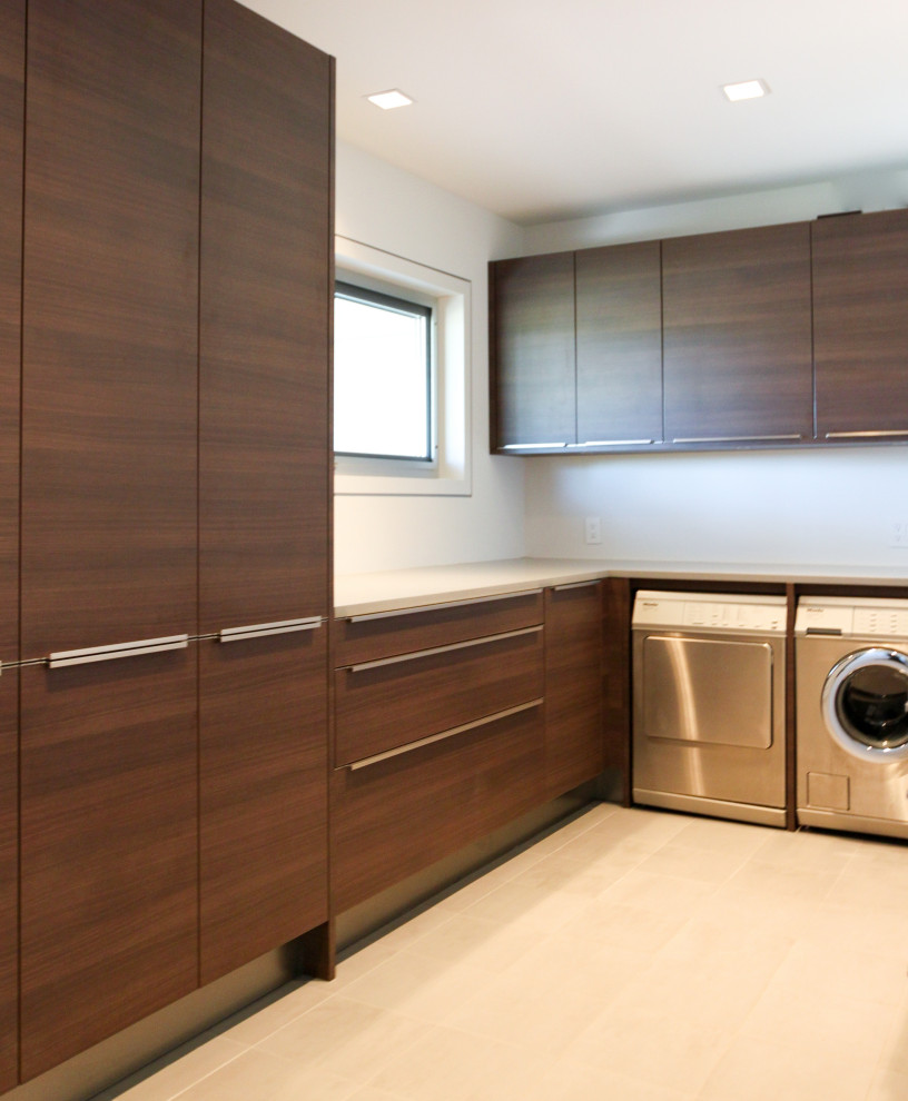 Exempel på en mellanstor modern grå u-formad grått tvättstuga enbart för tvätt, med en undermonterad diskho, släta luckor, skåp i mörkt trä, bänkskiva i kvarts, vita väggar, klinkergolv i porslin, en tvättmaskin och torktumlare bredvid varandra och grått golv