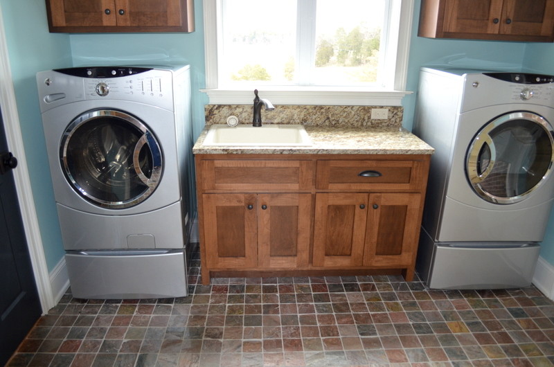 Mid-sized elegant single-wall slate floor utility room photo in Nashville with a single-bowl sink, shaker cabinets, medium tone wood cabinets, granite countertops, blue walls and a side-by-side washer/dryer