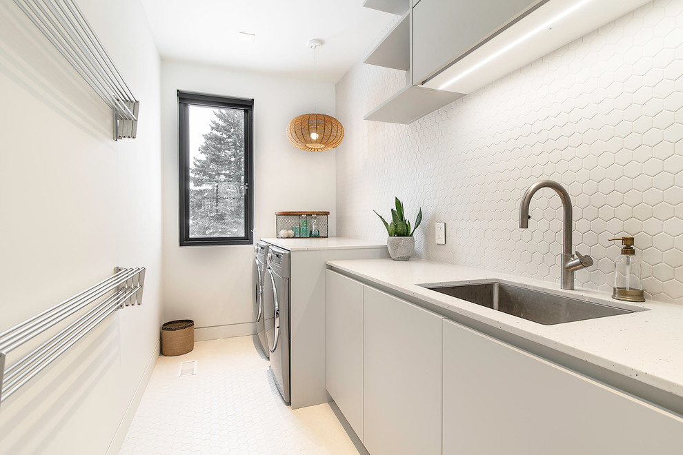 Einzeilige Moderne Waschküche mit Unterbauwaschbecken, flächenbündigen Schrankfronten, weißen Schränken, weißer Wandfarbe, Waschmaschine und Trockner nebeneinander, weißem Boden und weißer Arbeitsplatte in Toronto