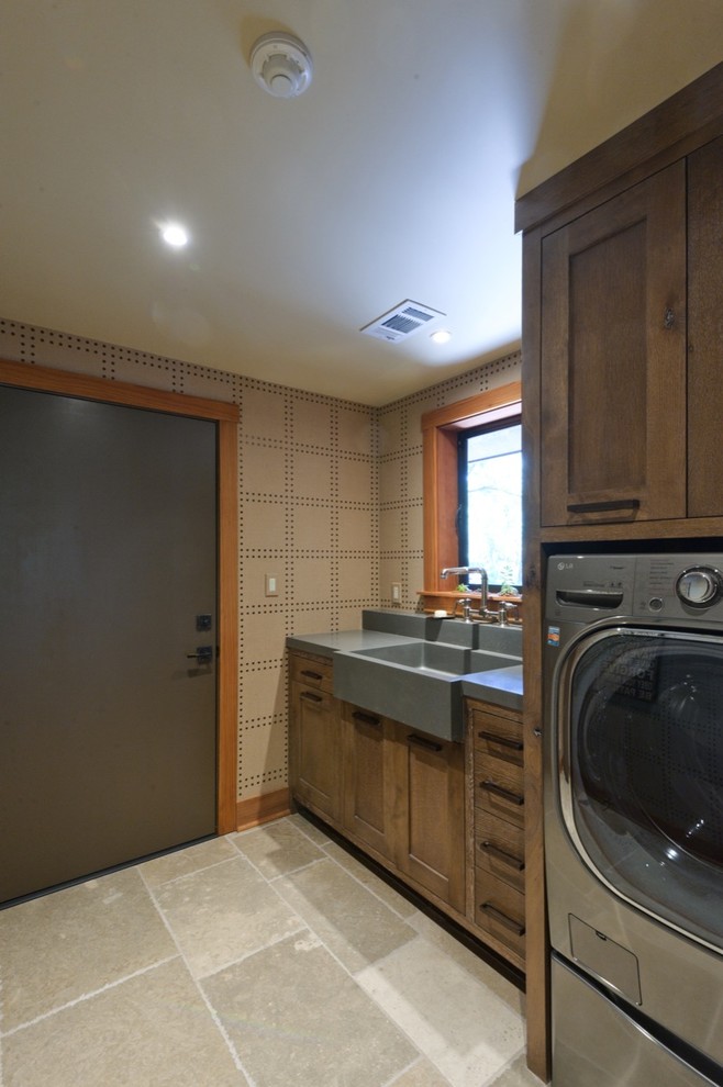 Bild på en linjär tvättstuga enbart för tvätt, med en rustik diskho, luckor med infälld panel, skåp i mellenmörkt trä, en tvättmaskin och torktumlare bredvid varandra och bänkskiva i betong