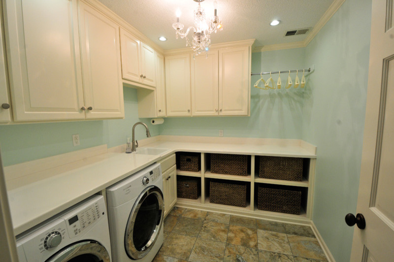 Immagine di una sala lavanderia shabby-chic style di medie dimensioni con lavello da incasso, ante con bugna sagomata, ante bianche, top in superficie solida, pareti blu, lavatrice e asciugatrice affiancate, pavimento in laminato e pavimento multicolore