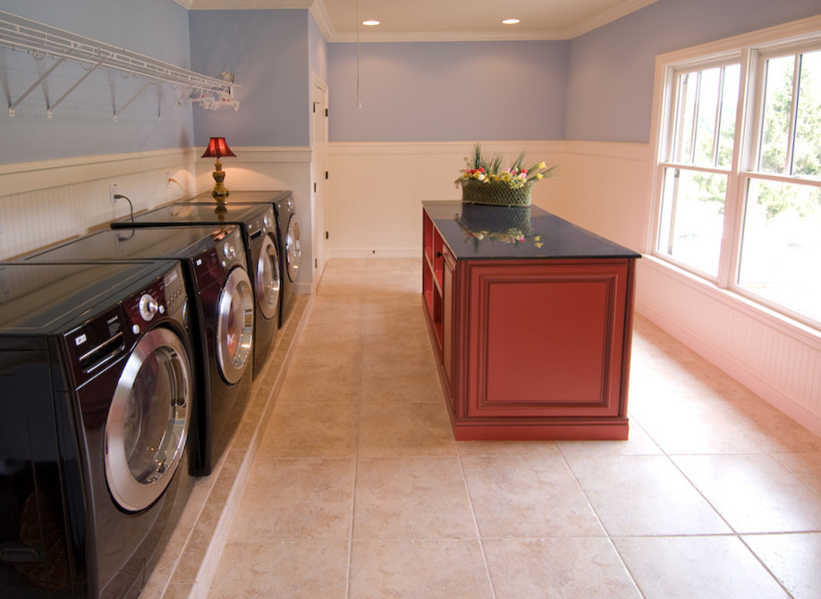 Exempel på en stor modern linjär tvättstuga enbart för tvätt, med bänkskiva i koppar, blå väggar, travertin golv, en tvättmaskin och torktumlare bredvid varandra och beiget golv